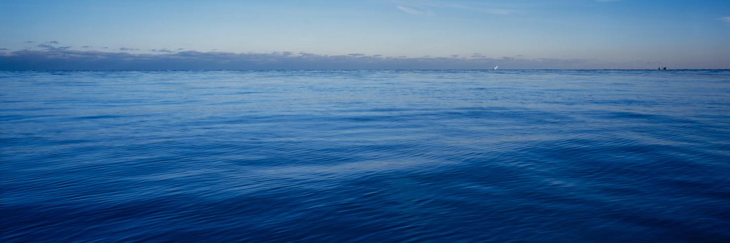 The vast expanse of Lake Michigan is captured with a clear horizon line and a few distant boats.