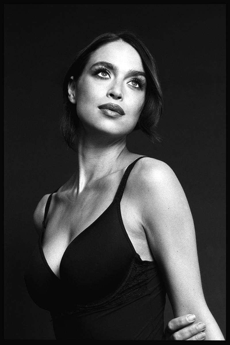 A woman wearing a bra looks up and to the right.
