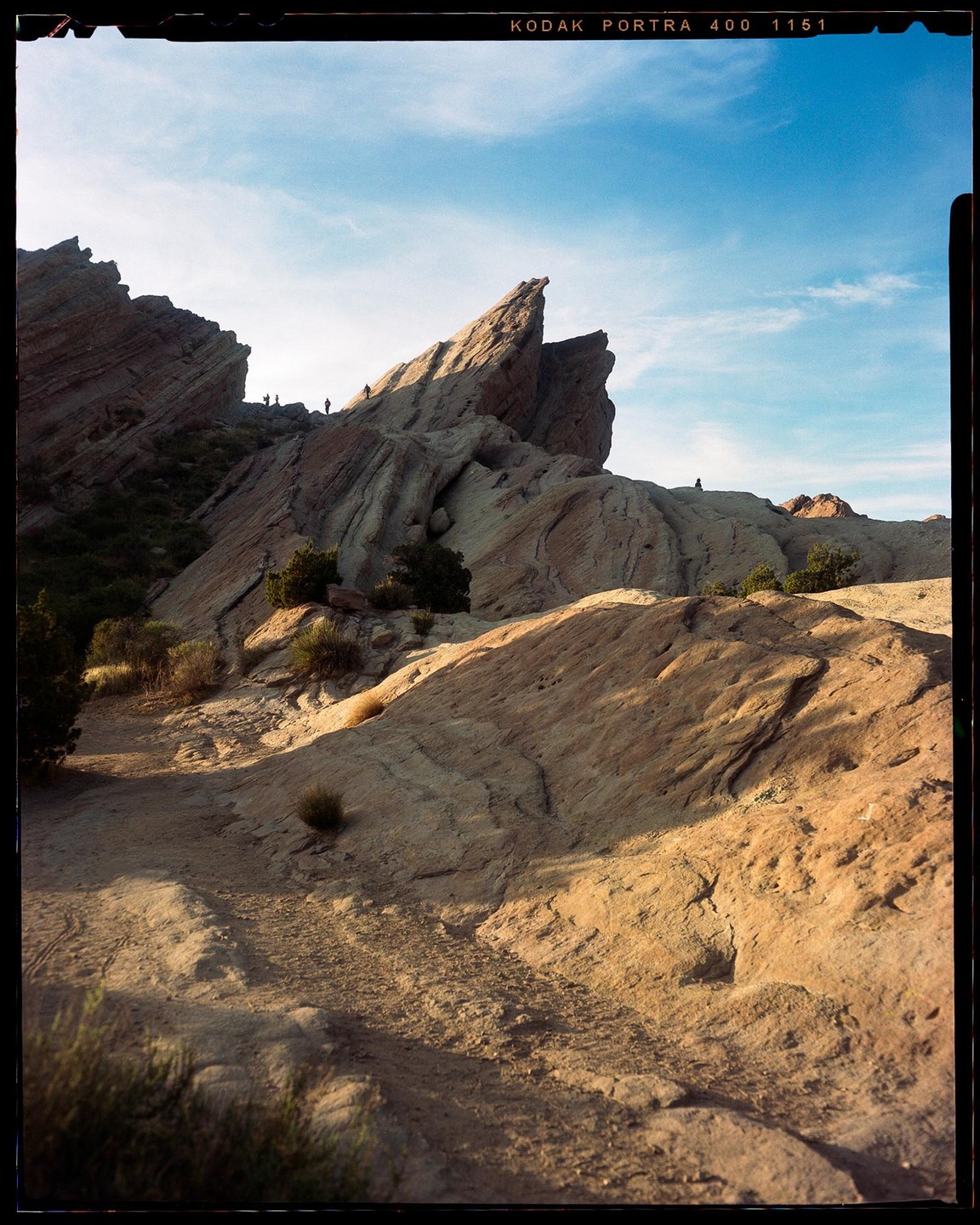 A group of people are hiking on a rocky mountain under a blue sky.