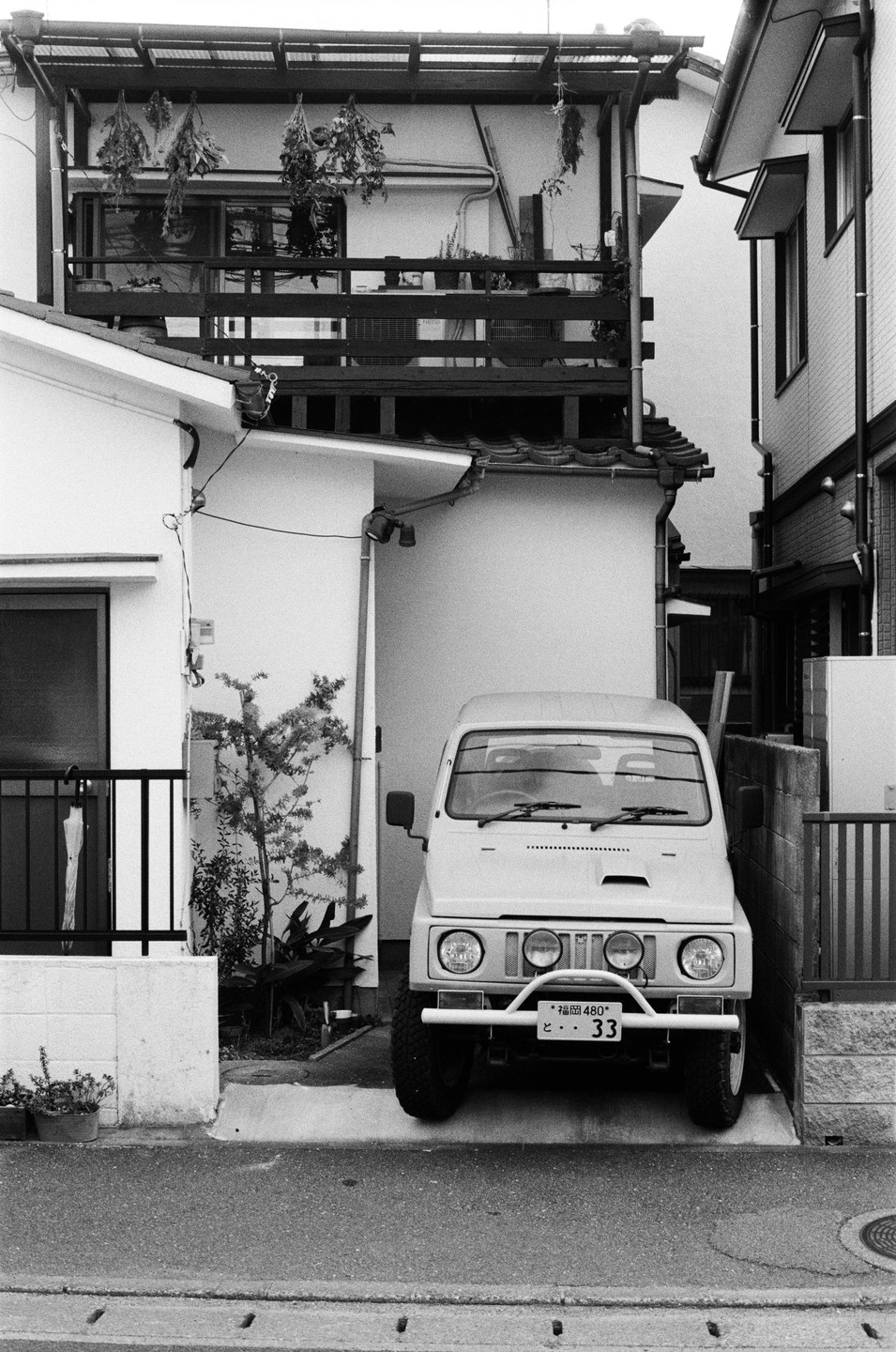 A small vehicle is parked in a narrow driveway between two buildings.