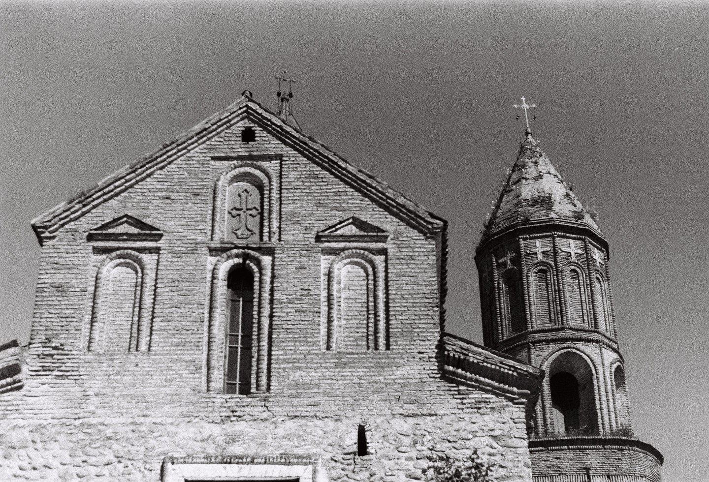 A brick church with a tall, conical tower stands against a clear sky.