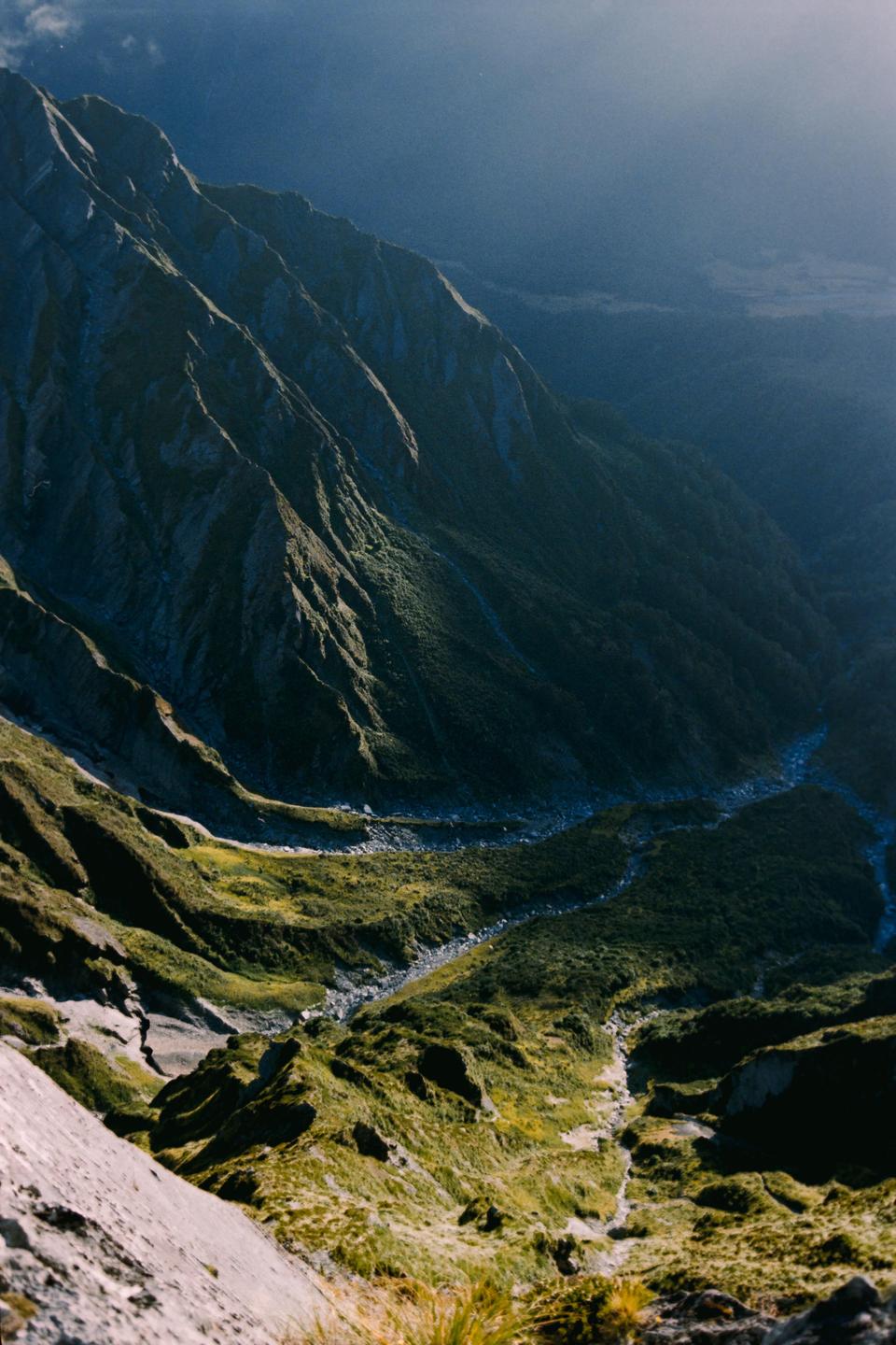 A valley with a river running through it is nestled between two mountains.
