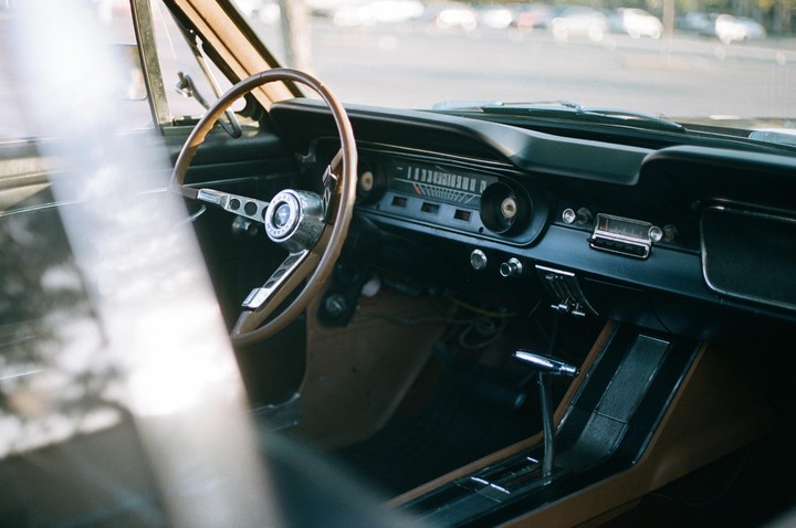 The interior of a vintage Ford Mustang is visible through the windshield.