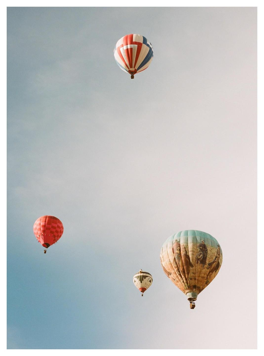 Four hot air balloons are visible against a clear sky.