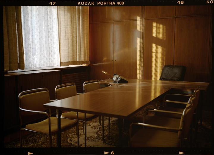 Sunlight streams through a window and across a large wooden table in a room with wood-paneled walls.