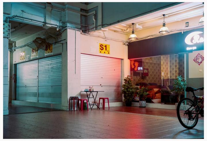 A closed storefront with a neon "SPA" sign and a bicycle parked nearby.