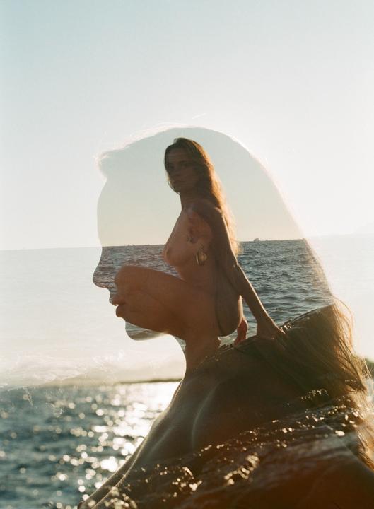 A double exposure shows a woman's profile superimposed over a nude woman crouching by the ocean.