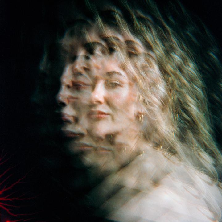 A woman with long hair is shown in a multiple exposure portrait with a dark background.
