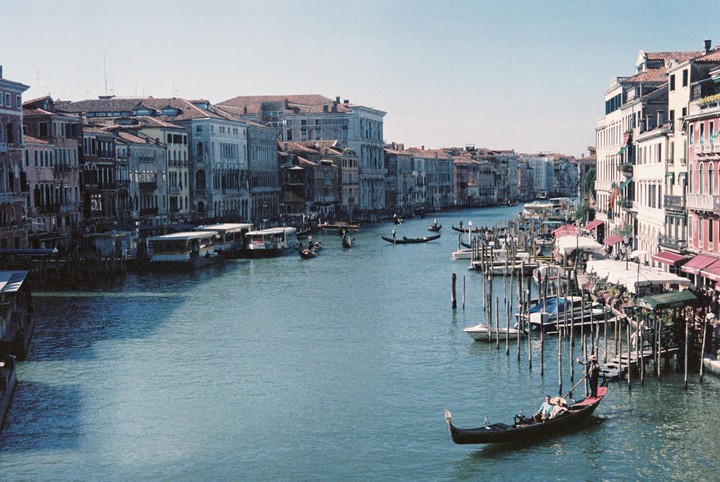 A wide canal in Venice is filled with gondolas and boats, flanked by historic buildings on both sides.