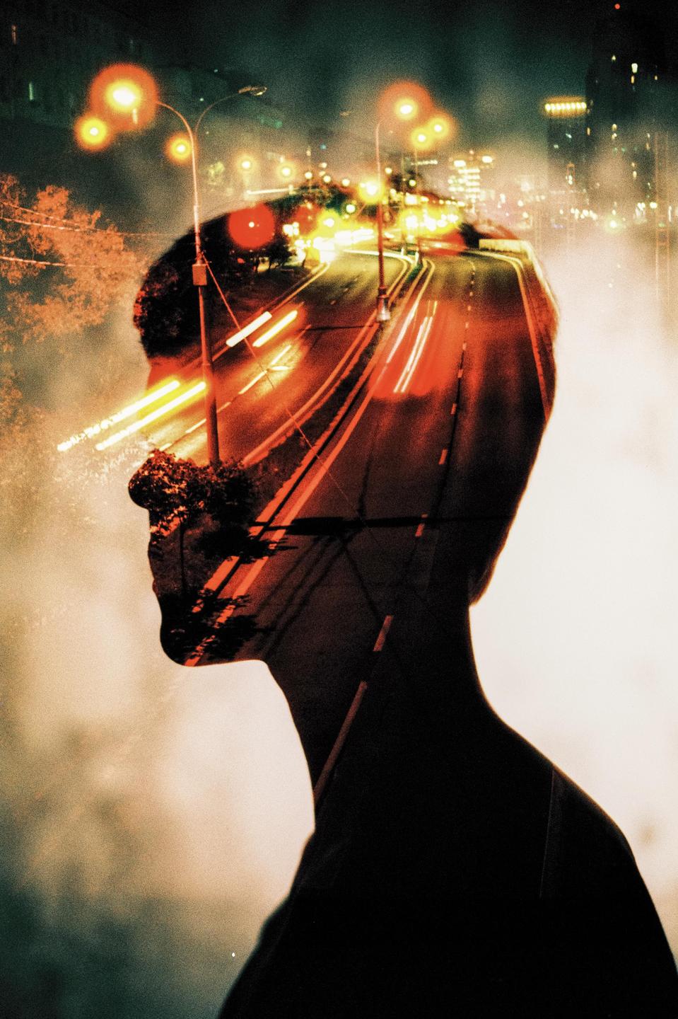 A double exposure shows the silhouette of a man's head overlaid with a night street scene featuring light trails from vehicles.