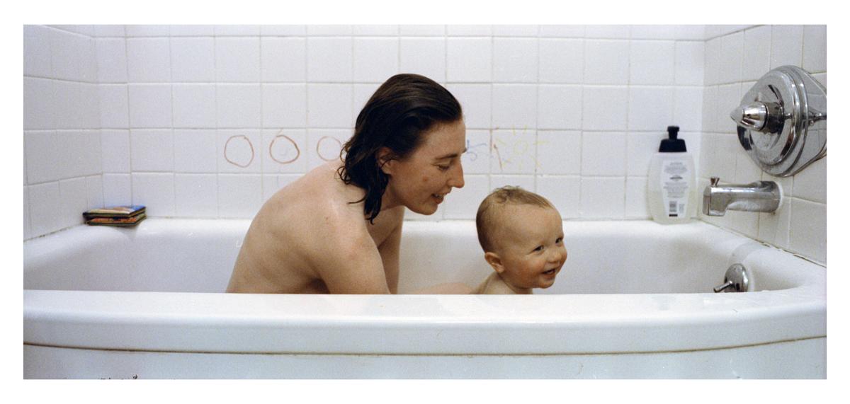 A woman and a baby are in a bathtub.