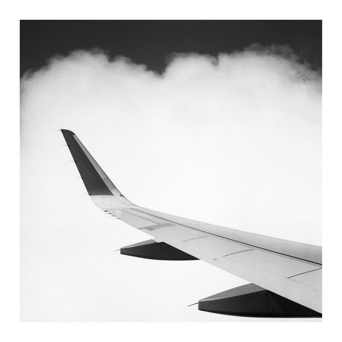 An airplane wing is visible against a cloudy sky.