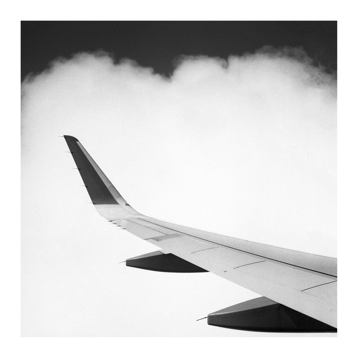 An airplane wing is visible against a cloudy sky.