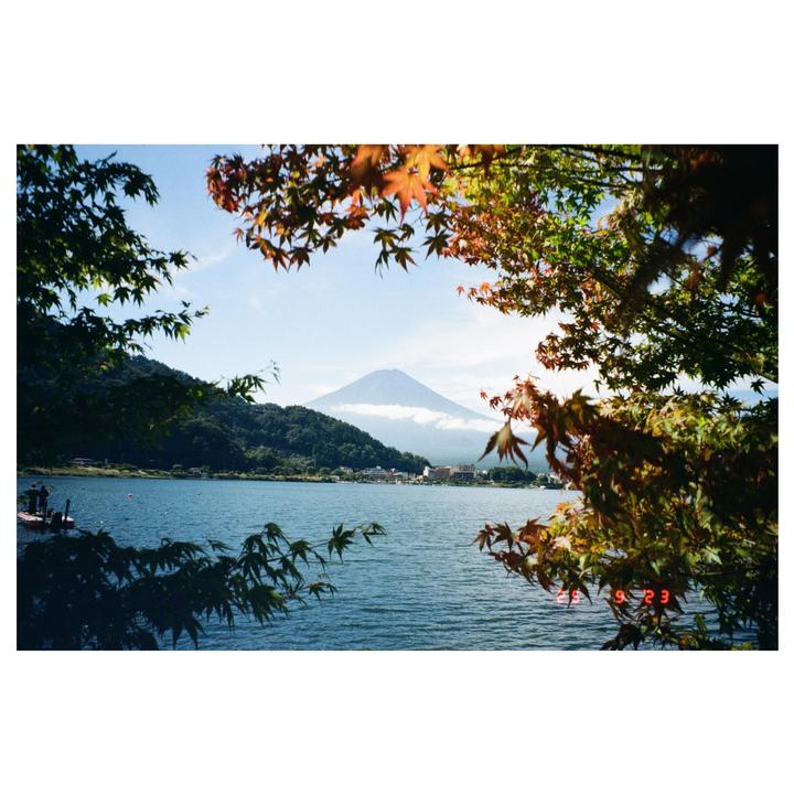 A lake with a mountain in the background is framed by autumn foliage.