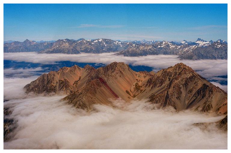 A mountain range with snow-capped peaks is visible above a layer of clouds.