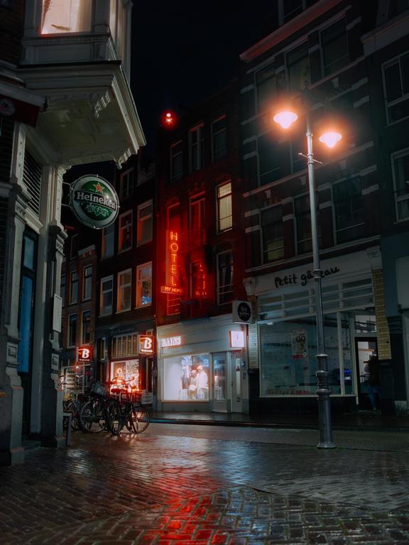 A street at night is illuminated by neon signs and streetlights, with bicycles parked along the sidewalk.
