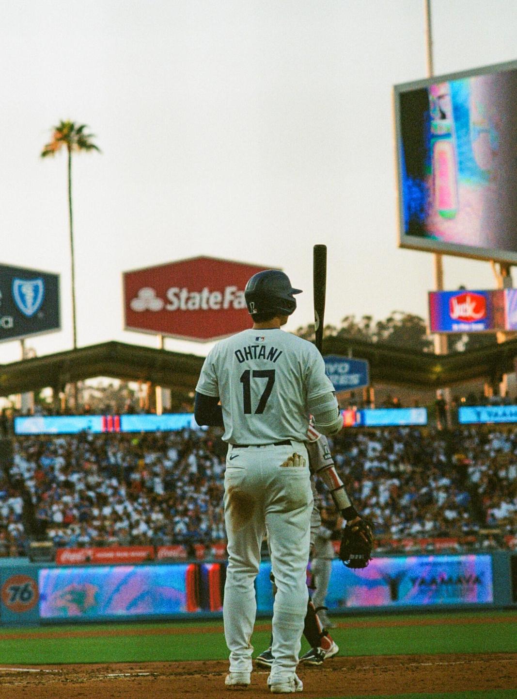 A baseball player wearing a white uniform with the number 17 and the name Ohtani on the back stands on a baseball field.