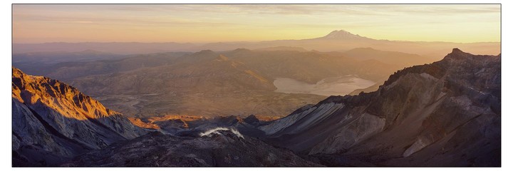 A panoramic landscape shows a vast mountainous terrain with a lake and a distant snow-capped peak under a golden sky.