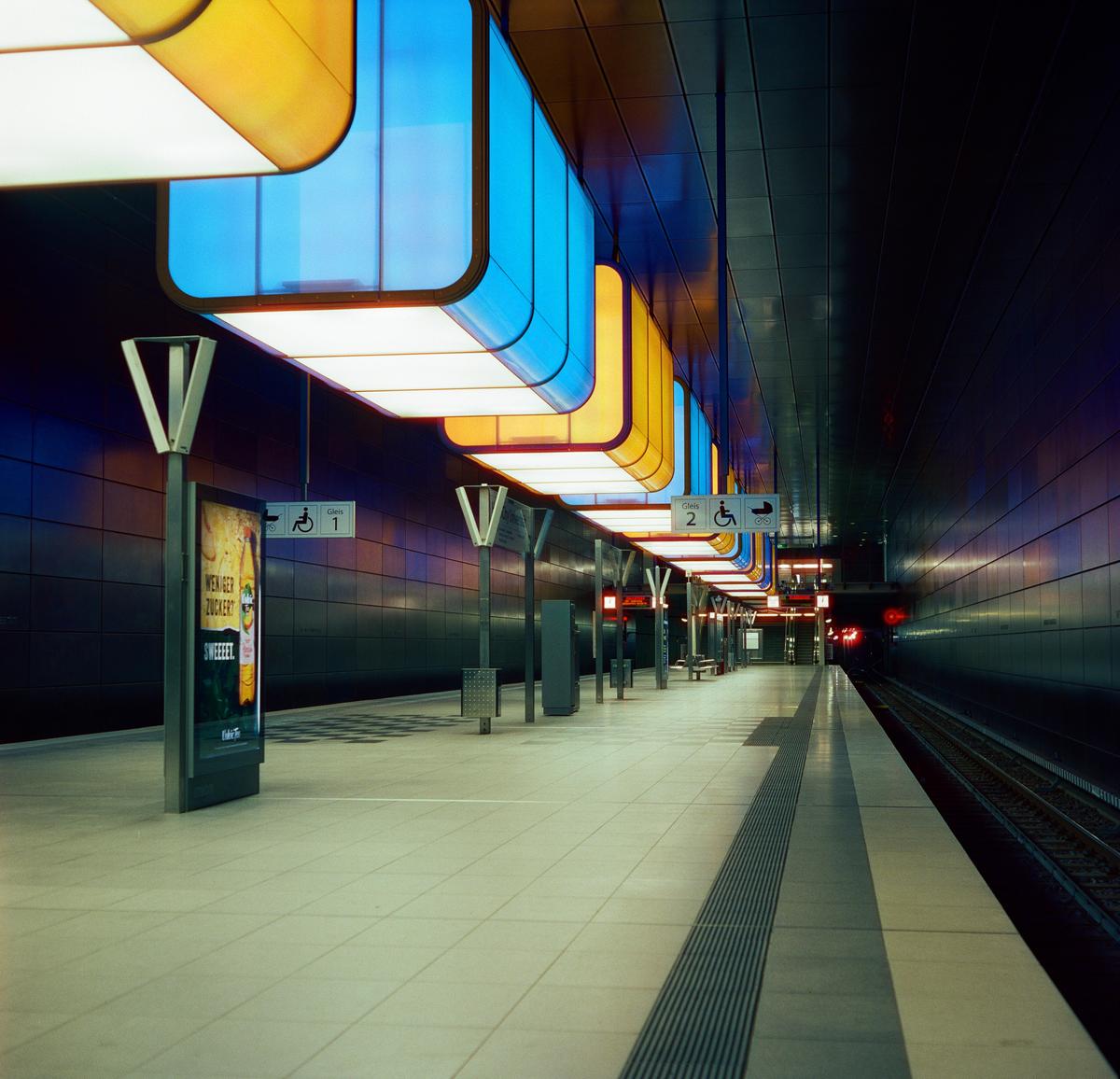 A subway platform is illuminated by colorful lights at night.