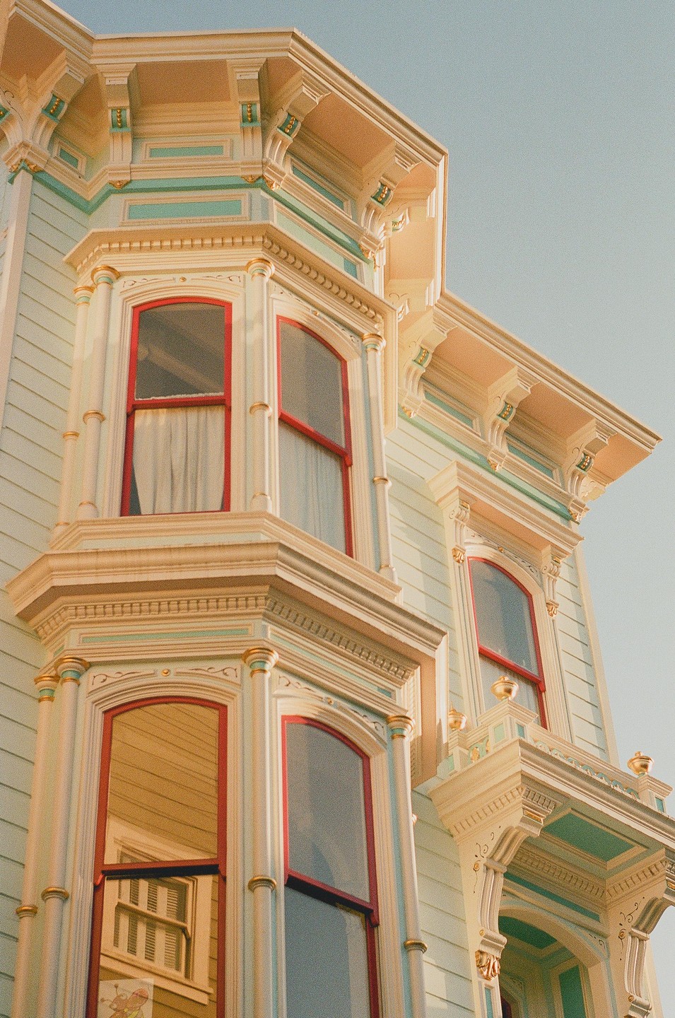 A detailed view of a Victorian house facade with bay windows and ornate trim is shown from a low angle.