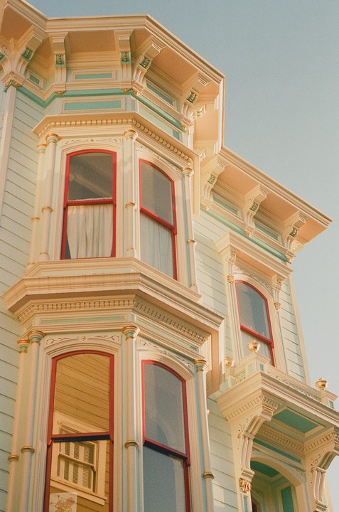 A detailed view of a Victorian house facade with bay windows and ornate trim is shown from a low angle.