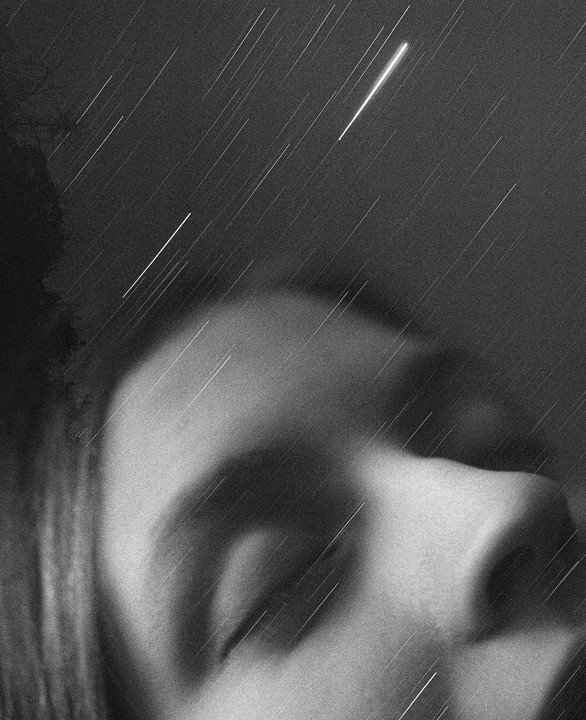 A woman's face is visible in the bottom right of the frame, with star trails and a bright meteor streaking across the night sky.
