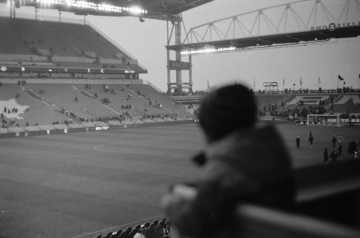 A blurred spectator watches a soccer game from the stands of BMO Field.