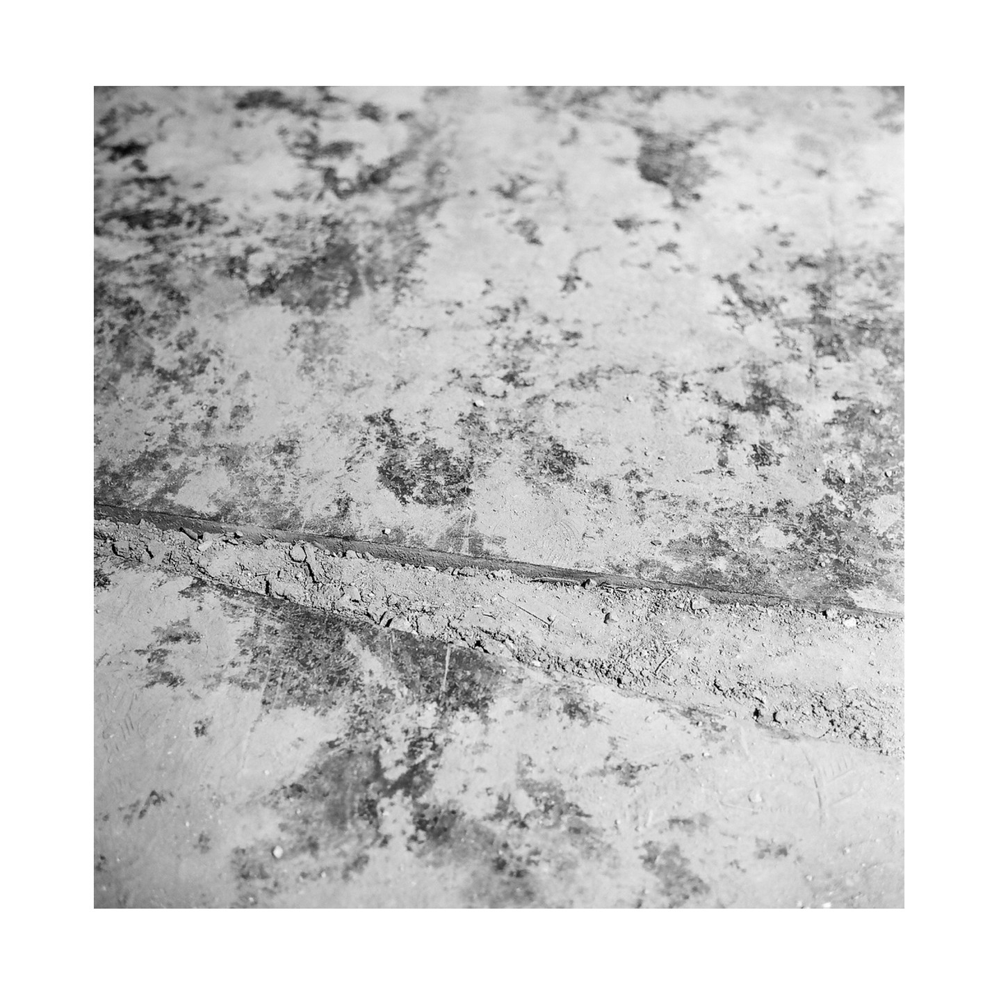 A close-up, high-angle view shows a dirty, textured floor with a thin line of debris running across it.
