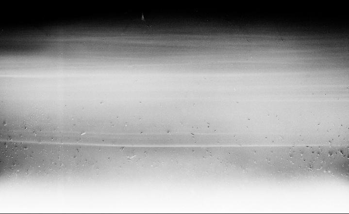 A black and white abstract image shows a gradient from dark to light with horizontal lines and small specks.