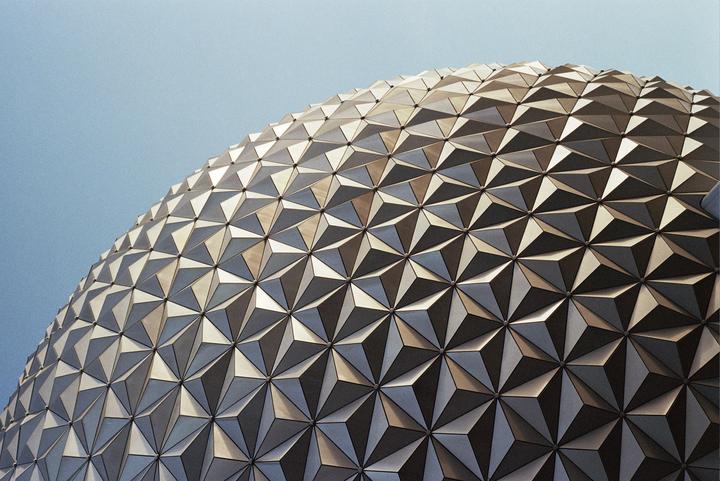 A geodesic dome with a triangular pattern covers the upper right portion of the frame against a clear sky.
