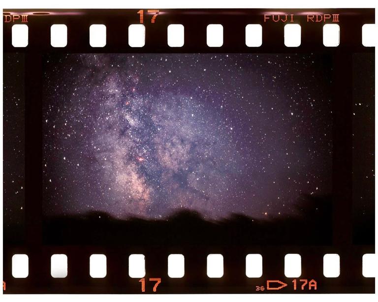 The Milky Way is visible in the night sky above a dark, undulating horizon.