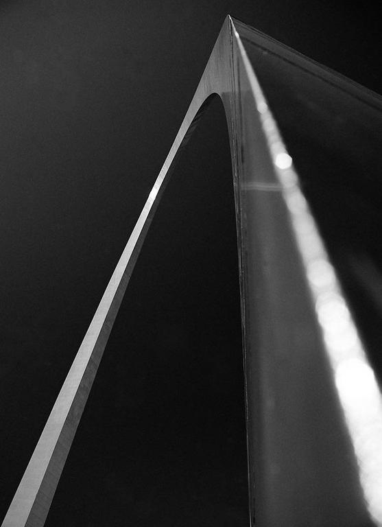 The Gateway Arch is visible from a low angle, with a bright reflection on its surface.