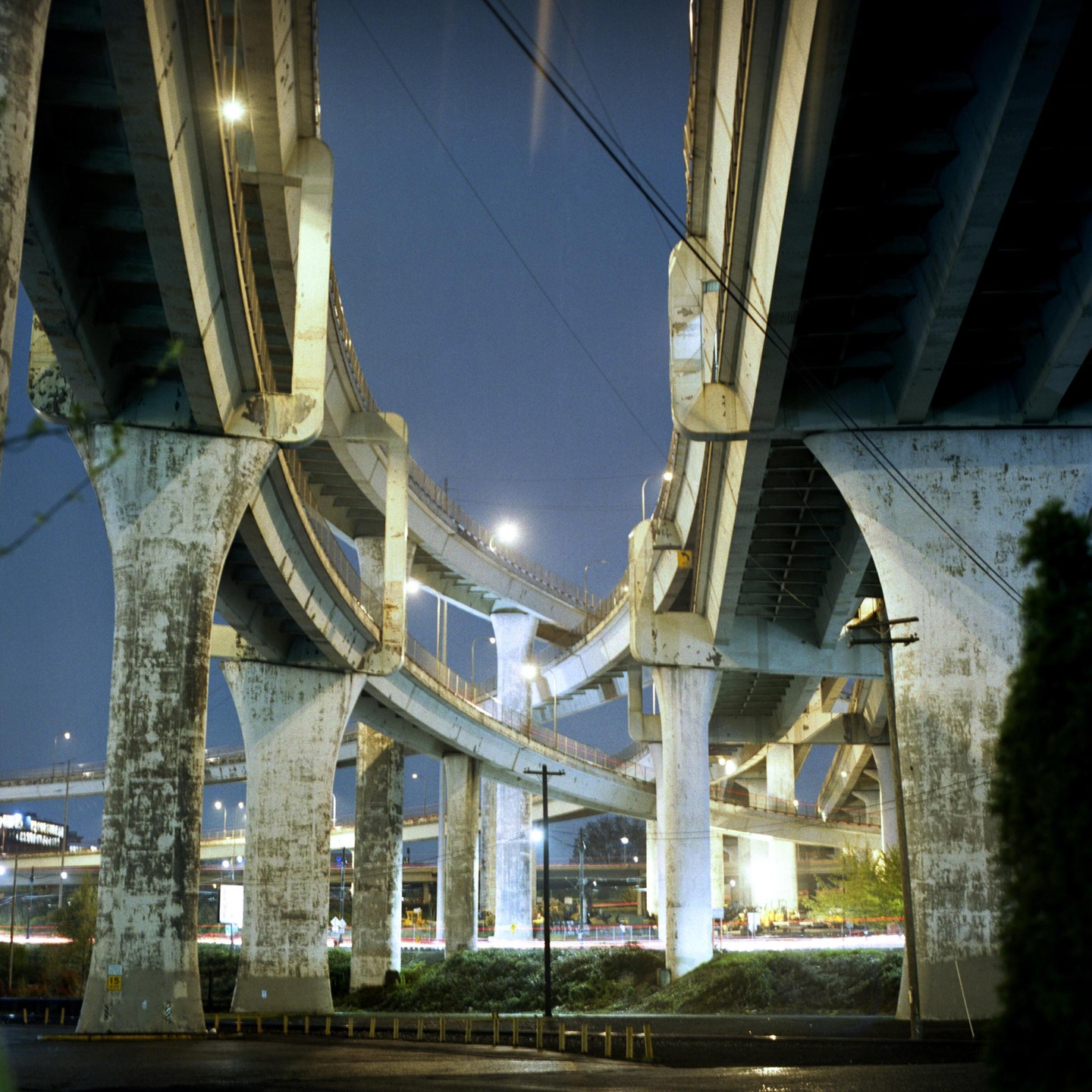 Multiple concrete highway overpasses are illuminated by streetlights at night.