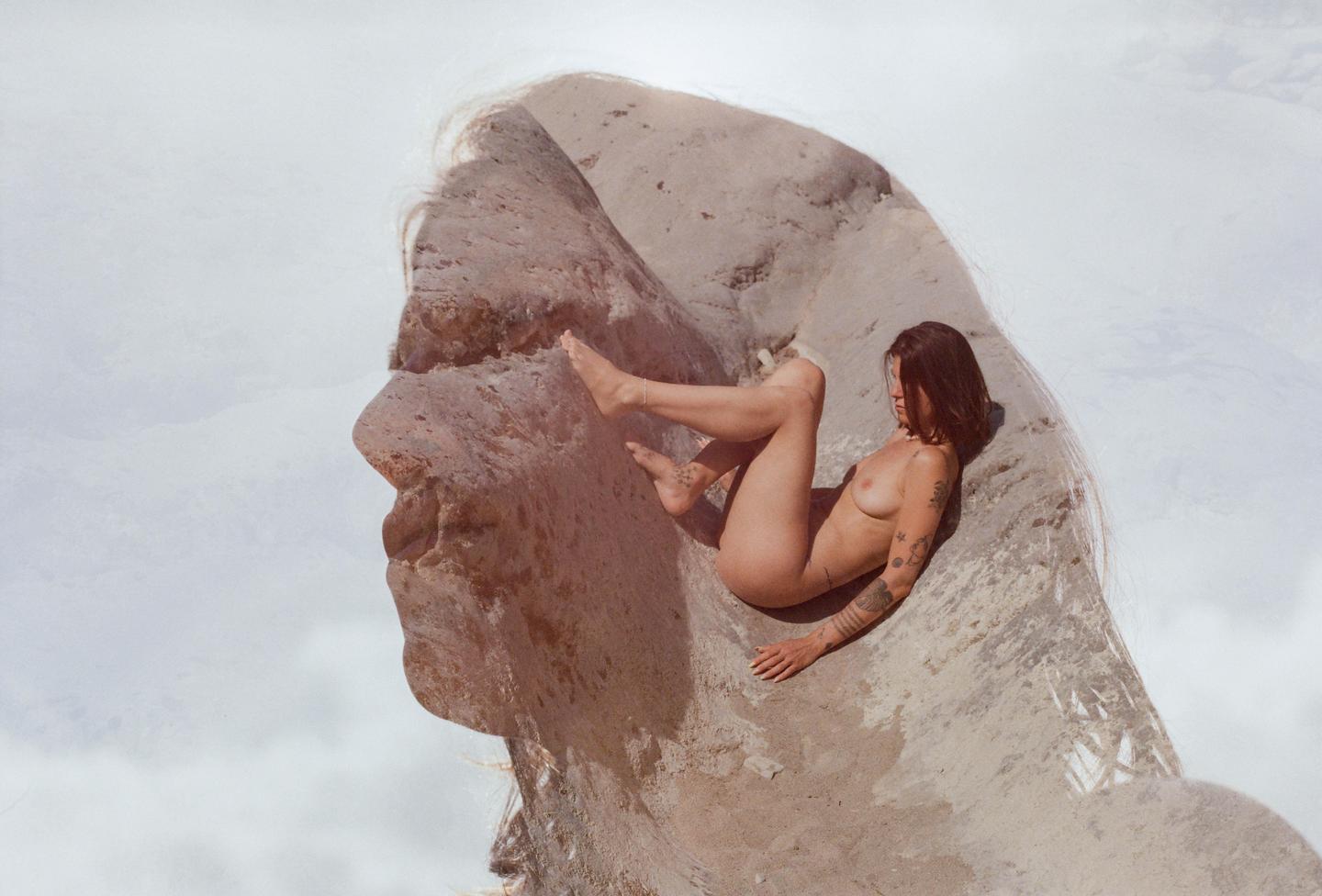 A nude woman is visible in a double exposure with a rock formation that resembles a face.