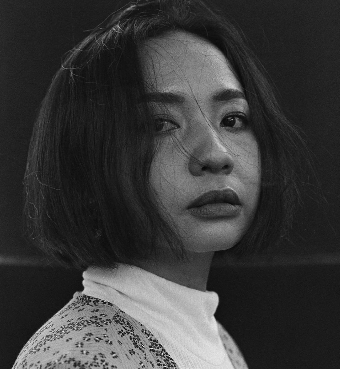 A woman with short hair and a turtleneck sweater looks directly at the viewer.