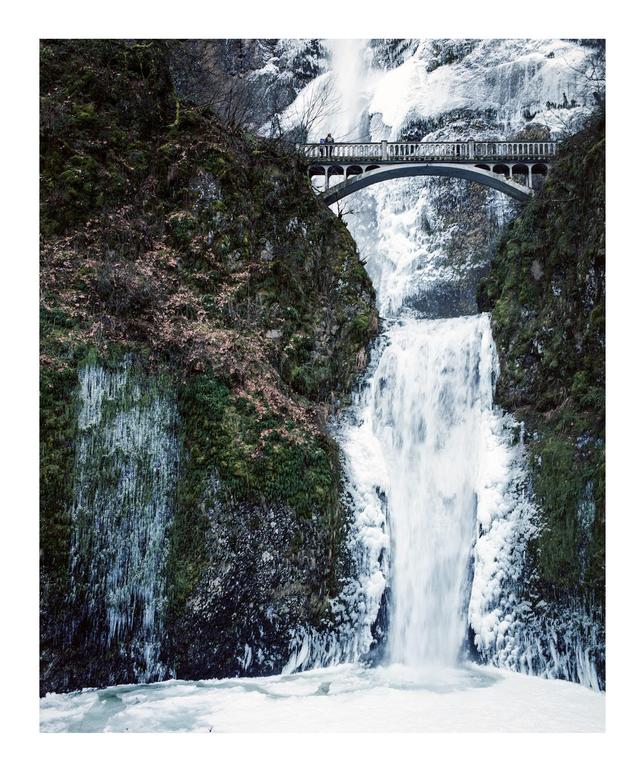 A bridge spans a frozen waterfall with icy cliffs on either side.