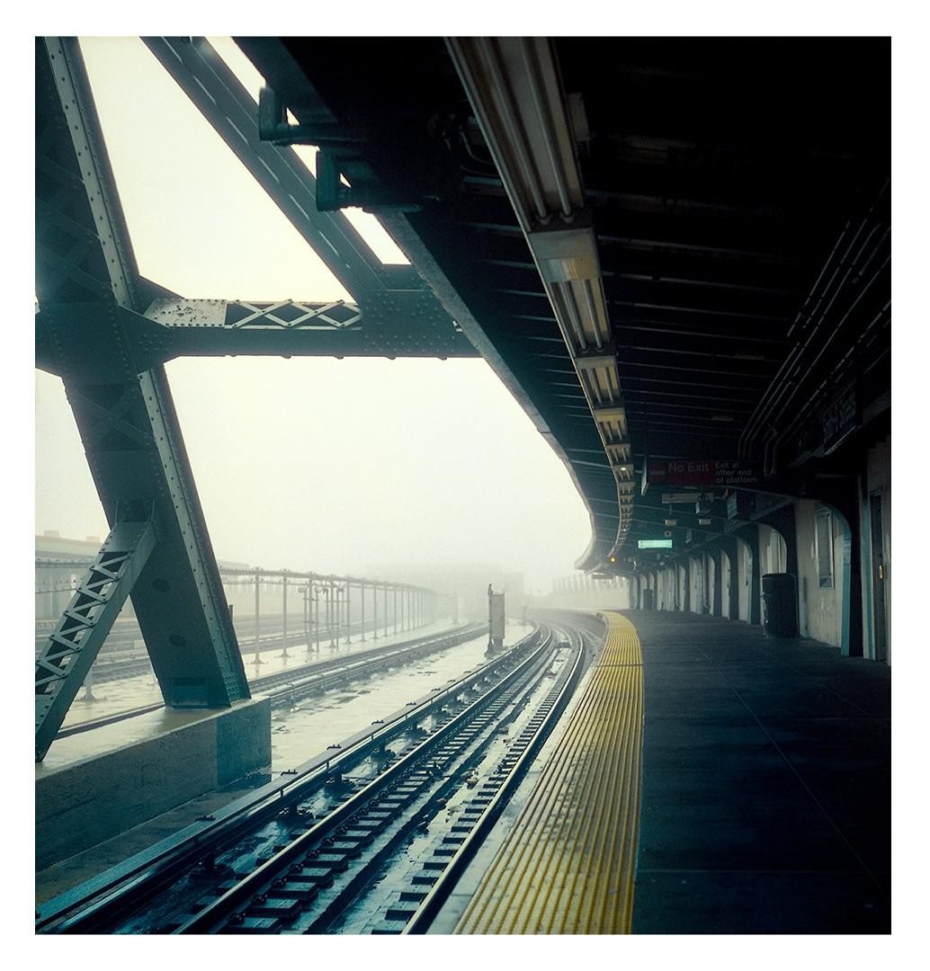 A subway platform and tracks are visible on a foggy day.