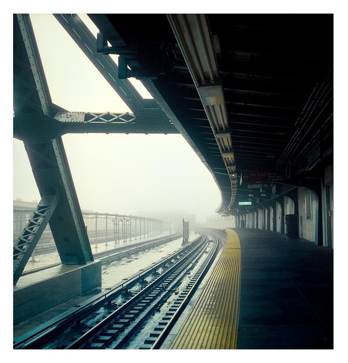 A subway platform and tracks are visible on a foggy day.