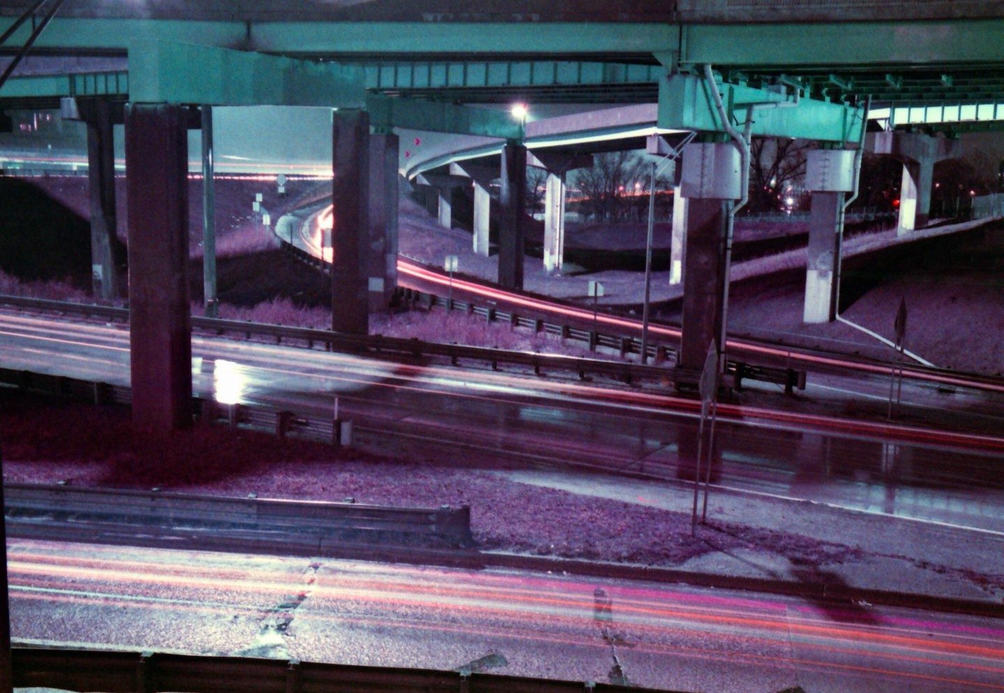 Light trails from vehicles are visible on a highway underpass at night.