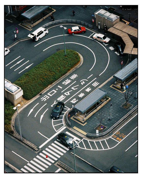 An aerial view shows a street with cars and people in front of a building.