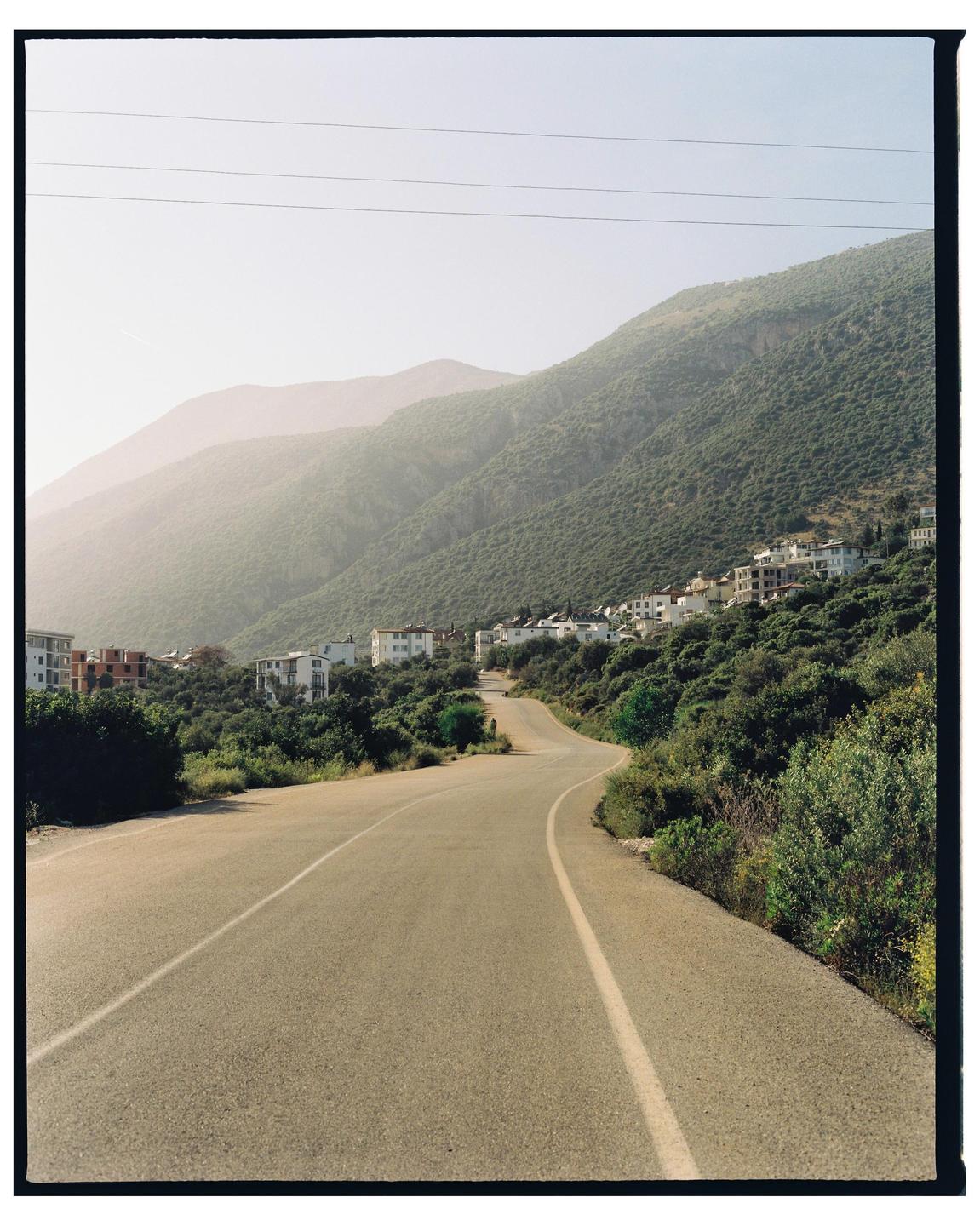 A winding road leads through a mountainous landscape with buildings nestled on the hillsides.
