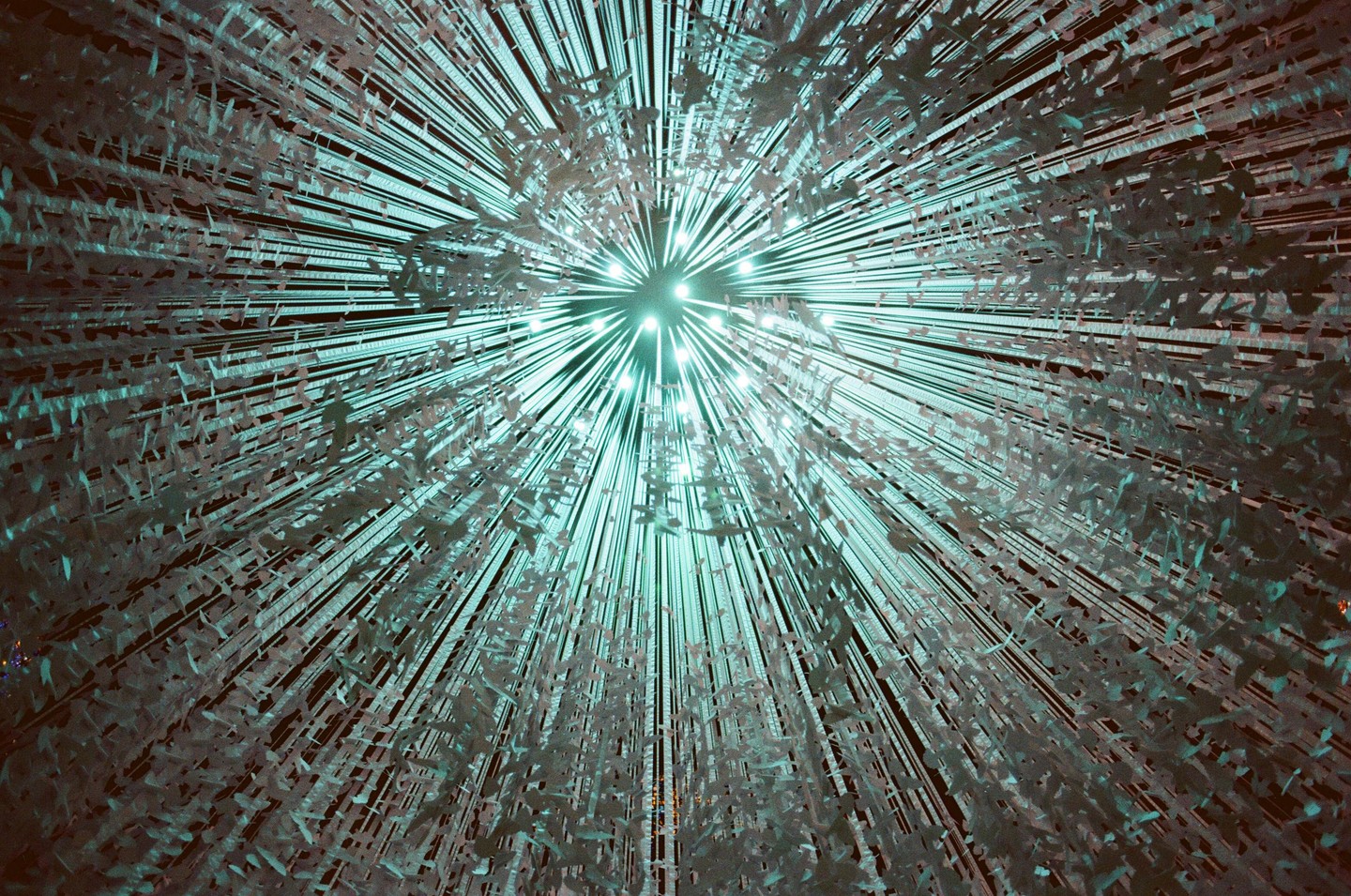 A chandelier with many small lights and hanging decorations is viewed from below.