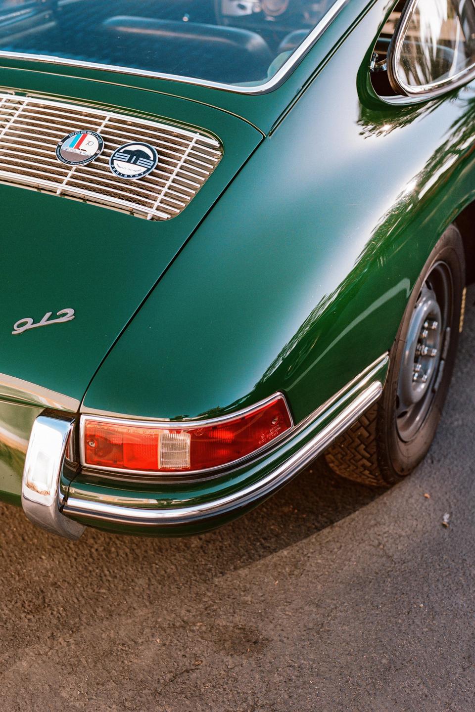 A close-up shot shows the rear of a green vintage car with a chrome bumper and taillight.