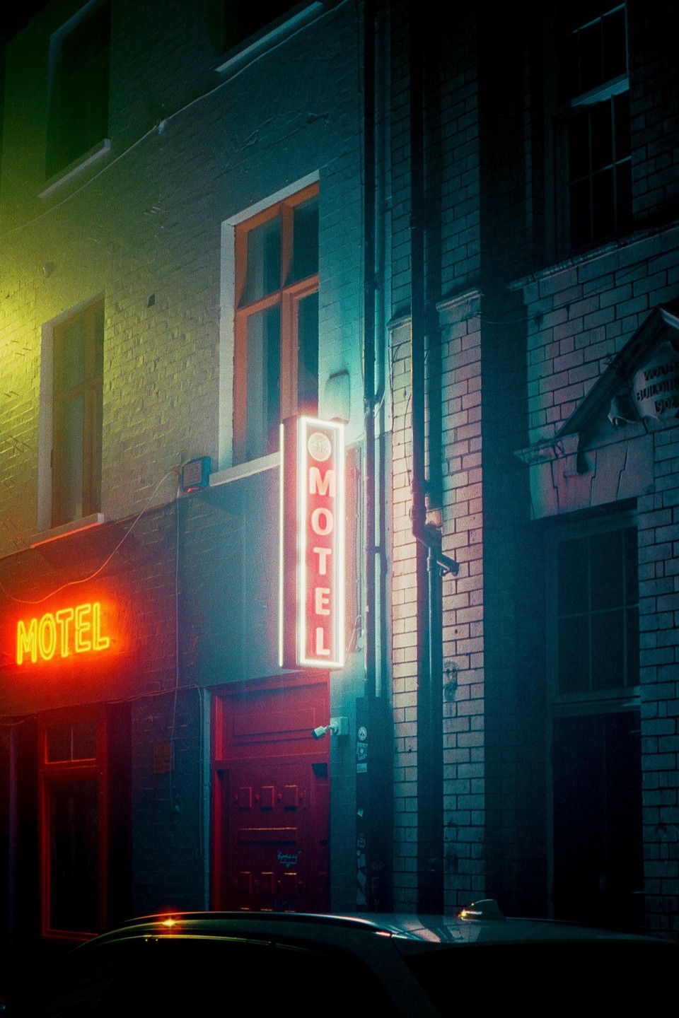 A neon motel sign illuminates a brick building at night.