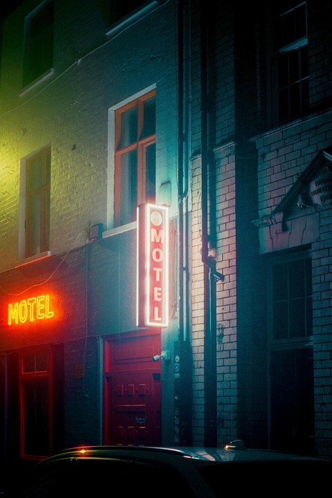 A neon motel sign illuminates a brick building at night.