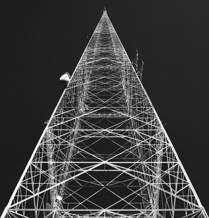 A radio tower extends into a dark sky.