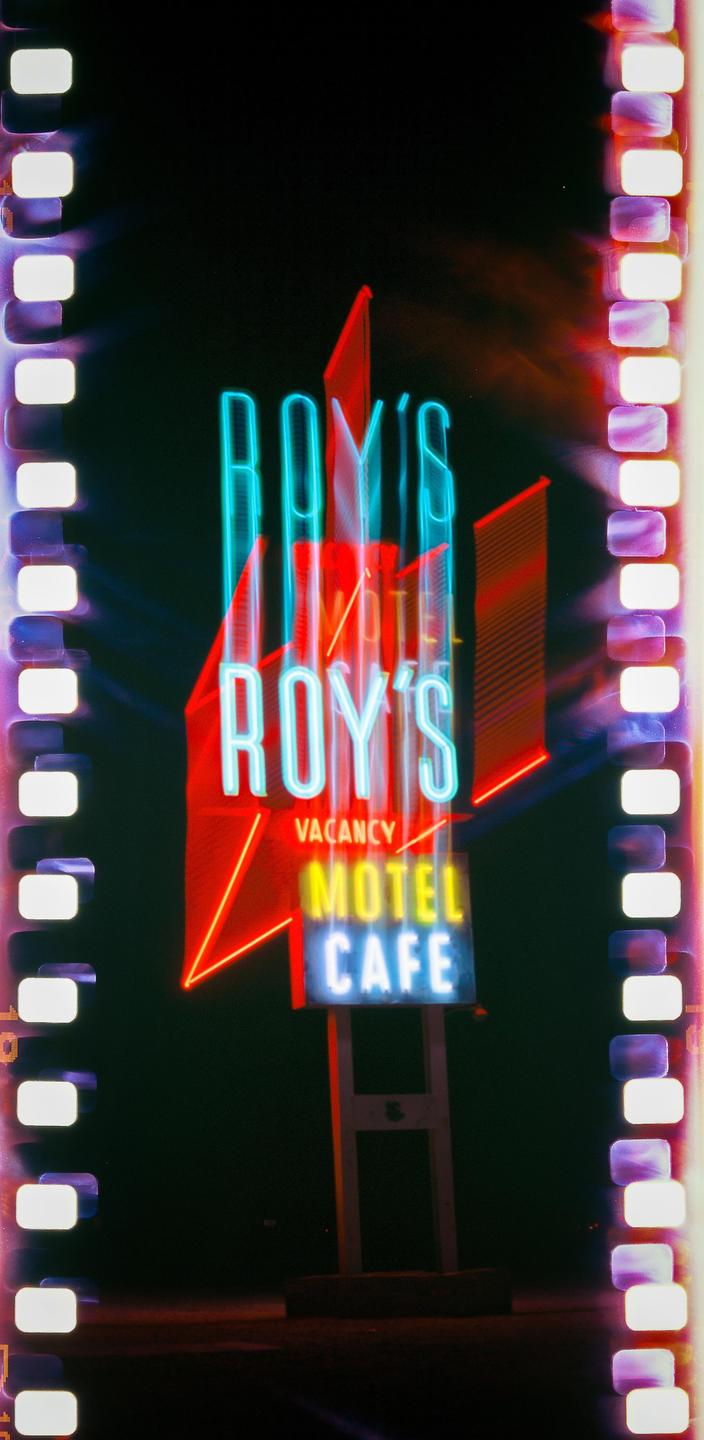 A neon sign for Roy's Motel and Cafe is illuminated at night.