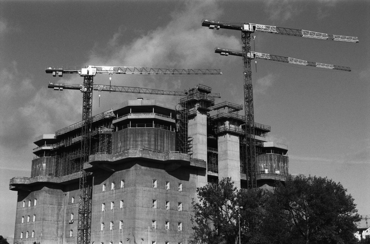 A large concrete bunker is under construction with several cranes towering above it.