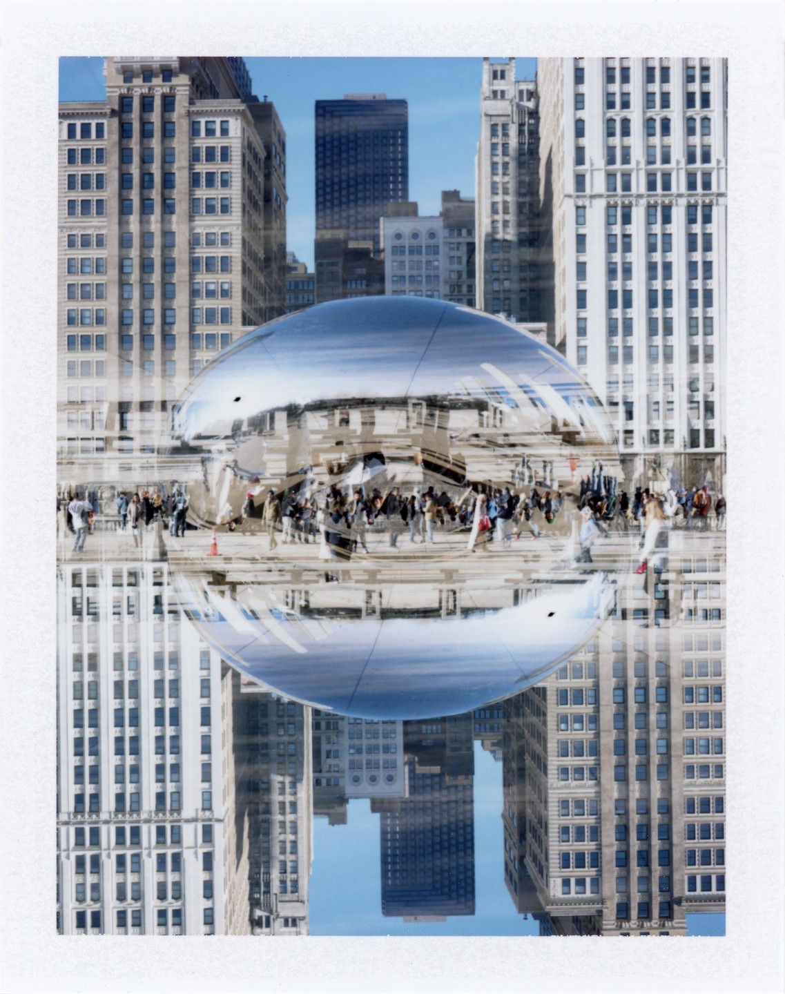 A double exposure shows a reflective bean-shaped sculpture with people and buildings in the background and reflected on its surface.