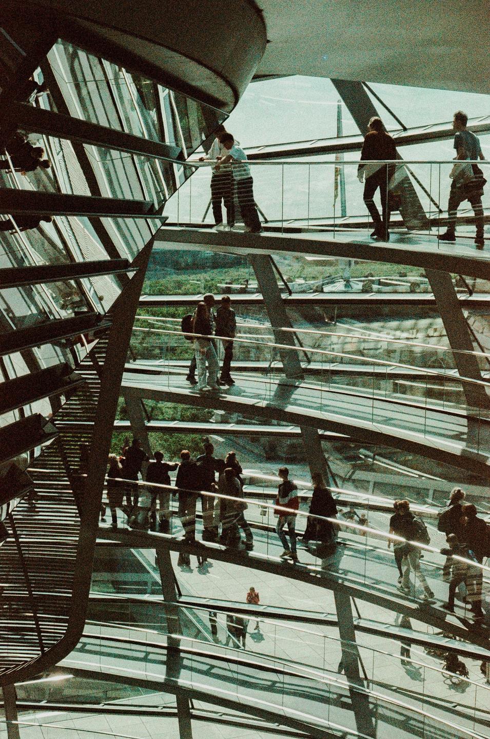 People walk on a spiraling ramp inside a glass dome structure.